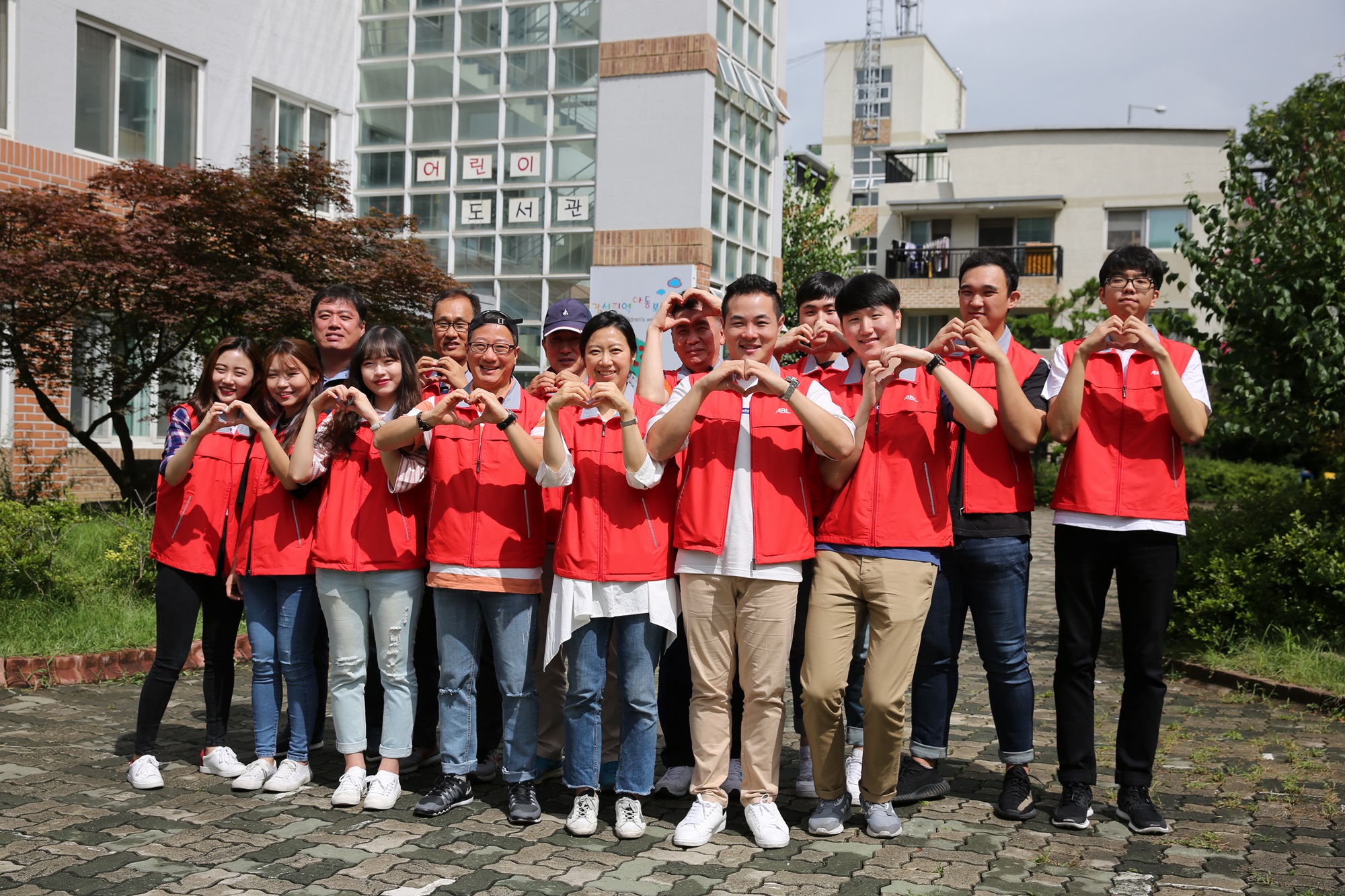 ABL직원들과 학생인턴들이 모여 손으로 하트를 만들며 밝게 웃으며 찍은 단체 사진
